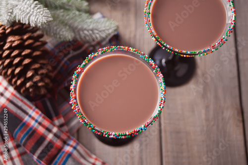 Glasses of winter season chocolate cocktail, christmas tree branch on the wooden background