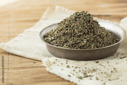 Dried chopped oregano in  bowl on wooden table