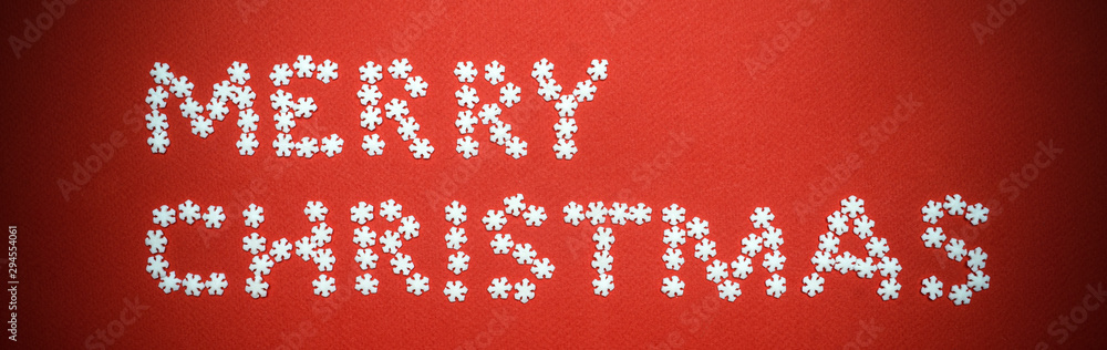 Christmas background. Merry Christmas lettering made of snowflakes on red background. Minimal concept, copy space