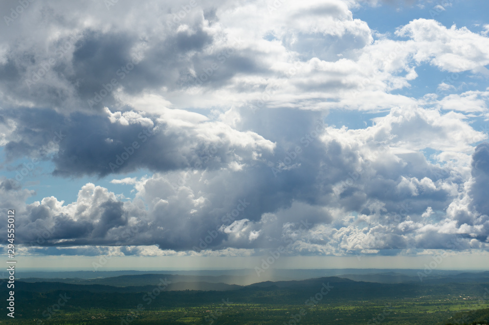 Dramatic beautiful sky with clouds and blue patches in between over a hilly green terrain Dramatic beautiful sky with clouds and blue patches in between over a hilly green terrain