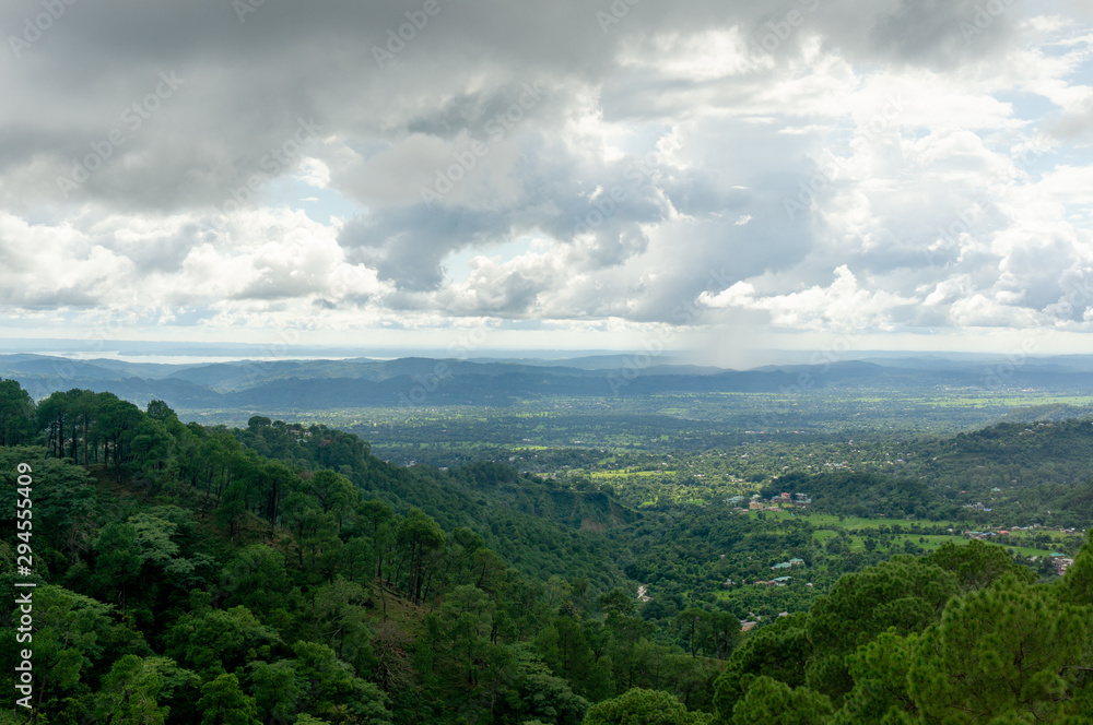 Aerial shot of tree covered mountains with clouds across the sky, shot at one of the famous hill stations of india