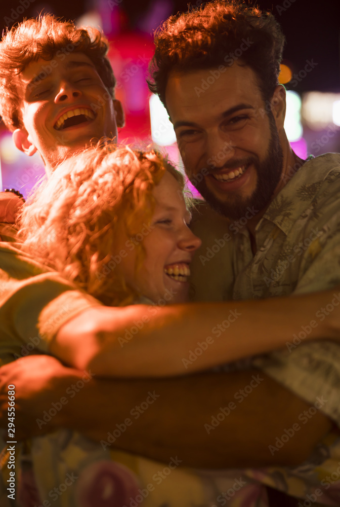 Young friends hug at night funfair