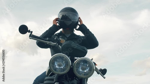 Young man with a motorcycle wears a helmet on his head. Close up slow motion footage. 4k.