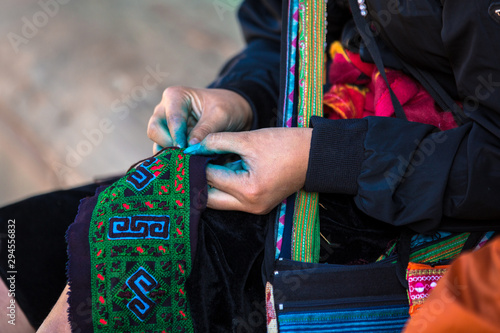 Ethnic Hmong woman weaving linen frabric with blue dye on her fingers seen in Sapa Lao Cai North Vietnam Indochina