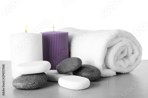 Towel  candles and spa stones on table against white background