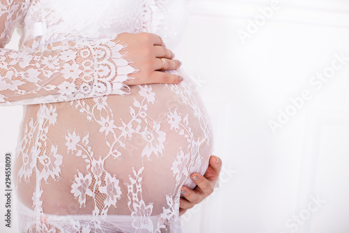 Pregnancy, motherhood and happy future mother concept. Pregnant woman holding her belly studio background photo.