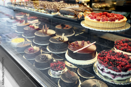 Different delicious cakes on display in cafe, view through window photo