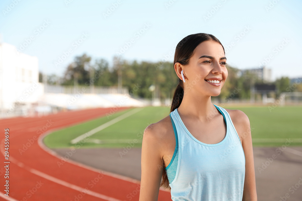 Young sportswoman with wireless earphones at stadium Young sportswoman with wireless earphones at stadium