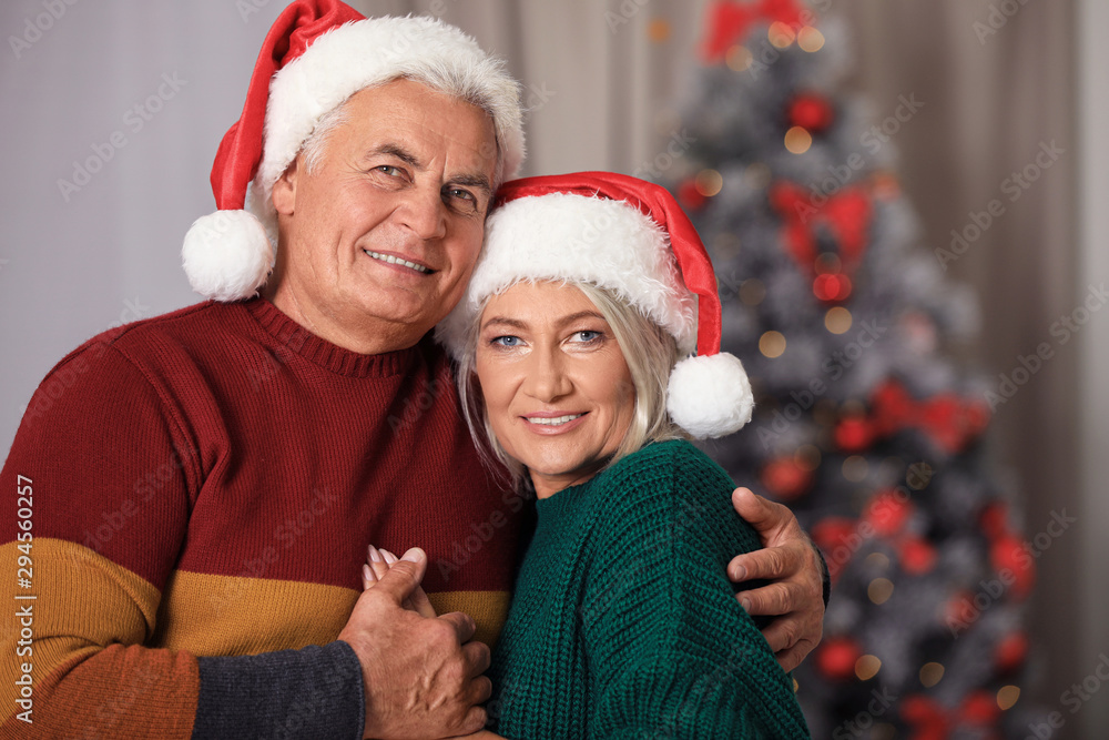 Happy mature couple in Santa hats at home. Christmas celebration Happy mature couple in Santa hats at home. Christmas celebration