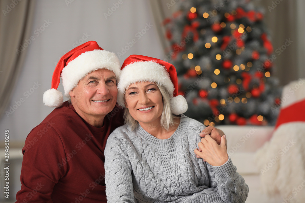 Happy mature couple in Santa hats at home. Christmas celebration Happy mature couple in Santa hats at home. Christmas celebration