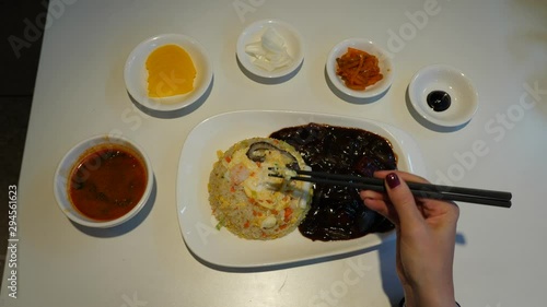 Asian set menu, seafood stir fried rice with soup and small cups of snacks. Top view of cheap meal served in small restaurant at Seoul. Woman start eating using chopsticks photo