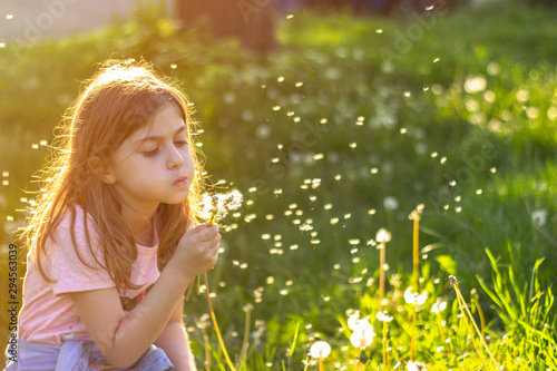 Little girl in the park on the sunny sprind day; blowing dandelion