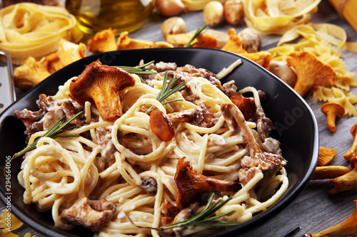 pasta with organic chanterelles. portion of spaghetti pasta with fried chanterelles in a creamy garlic sauce with cheese on a table photo