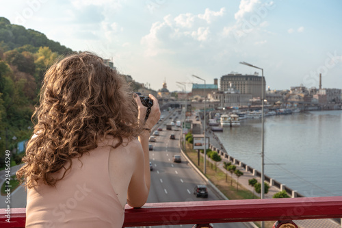 Young woman on the bridge taking photo of the city at summer with digital camera.  © MoonfliesPhoto