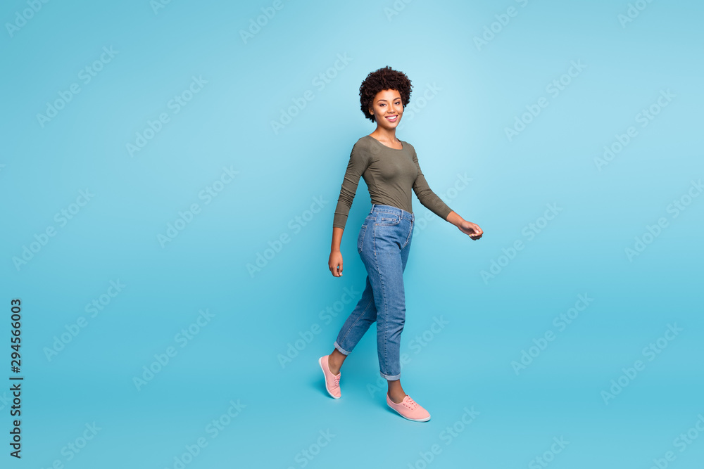 Full length body size photo of cheerful cute charming nice black woman going turned walking smiling friendly toothily isolated over vivid color blue background