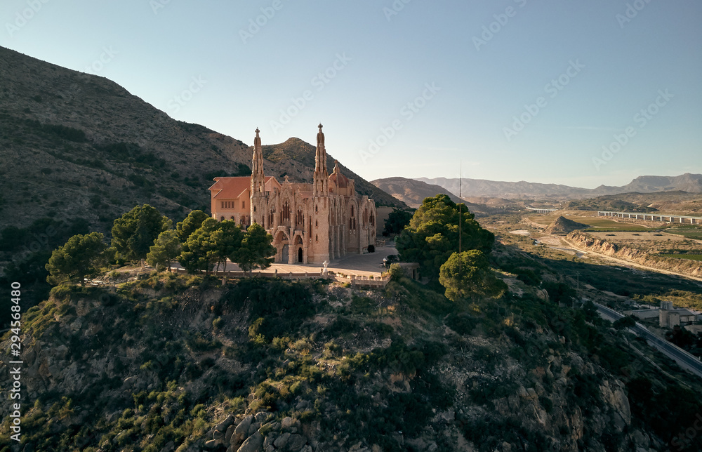 Aerial drone point of view Sanctuary of Santa Maria Magdalena rises among top of rocky mountain in Novelda town, spanish Art Nouveau masterpiece in Spain, Province of Alicante