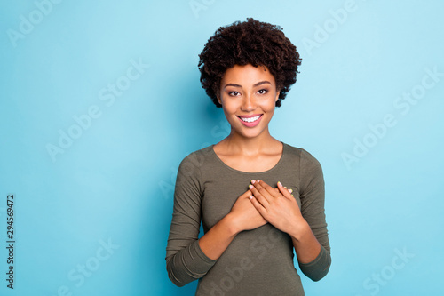 Portrait of positive peaceful calm afro american girl put her hands on chest feel good thankful wear casual lifestyle outfit isolated over blue color background