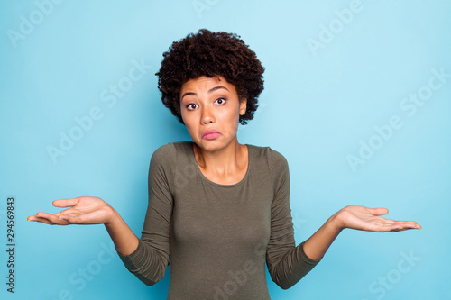 I dont care. Portrait of doubtful negative curly hair afro american girl cant choose answer solve trouble shrug shoulders hold hands hesitate wear beautiful outfit isolated blue color background photo