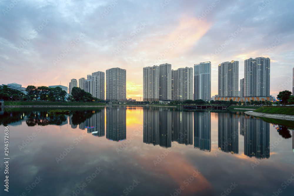 Buildings with reflections on lake at sunset at Thanh Xuan park. Hanoi cityscape at twilight period