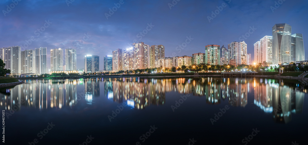 Fototapeta premium Buildings with reflections on lake at twilight at Thanh Xuan park. Hanoi cityscape at twilight period