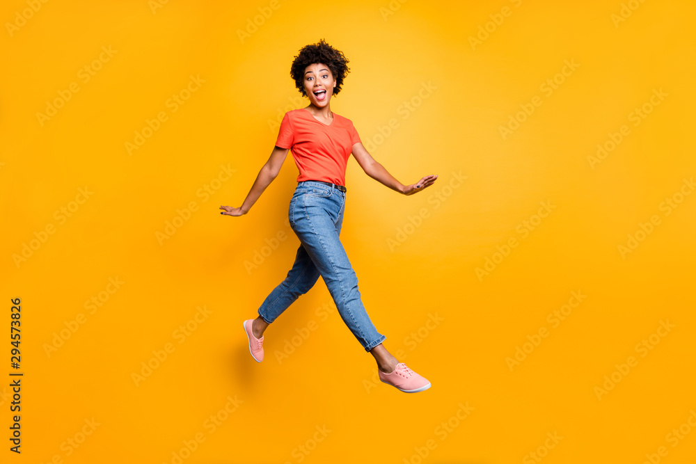 Full body photo of funny funky cheerful lady jump go walk feel crazy have free time wear spring clothes sneakers isolated over yellow color background