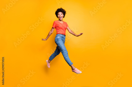 Full body photo of funny funky cheerful lady jump go walk feel crazy have free time wear spring clothes sneakers isolated over yellow color background