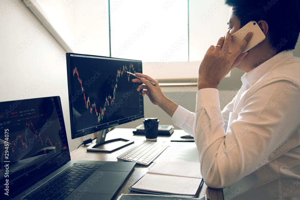Agent trader man talking at telephone and checking business stock data on computer in office room. Agent trader man talking at telephone and checking business stock data on computer in office room.