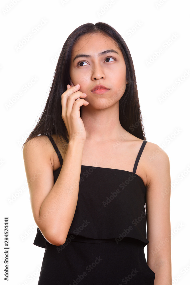 Thoughtful young Asian teenage girl talking on mobile phone