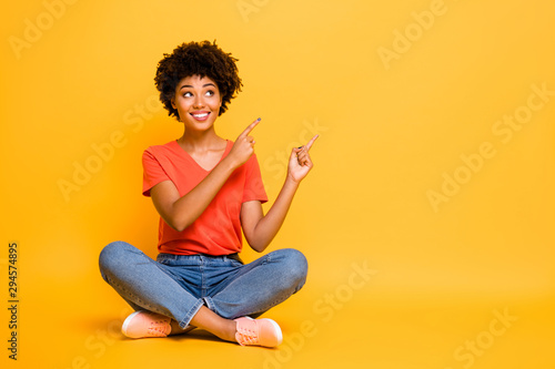 Copyspace photo of charming cheerful attractive gorgeous girlfriend sitting with legs crossed wearing jeans denim footwear isolated with yellow bright color background