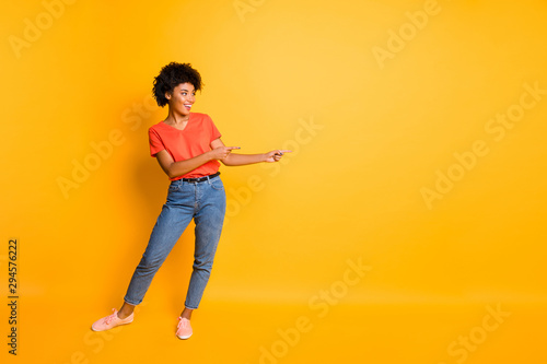 Copyspace photo of cheerful charming trendy cute fascinating girlfriend pointing at something smiling toothily isolated over yellow bright color background