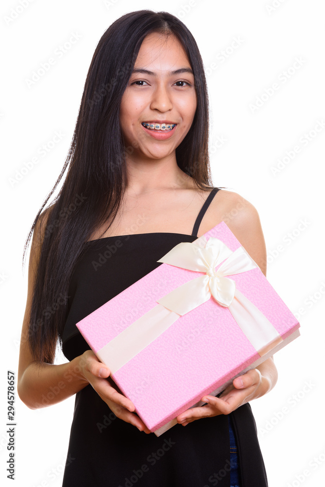 Studio shot of young happy Asian teenage girl smiling while hold Studio shot of young happy Asian teenage girl smiling while hold