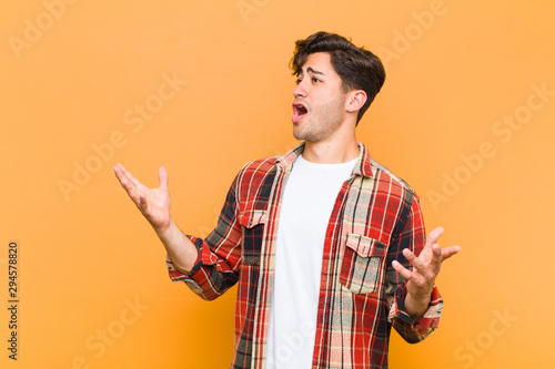 young handsome man performing opera or singing at a concert or show, feeling romantic, artistic and passionate against orange background photo