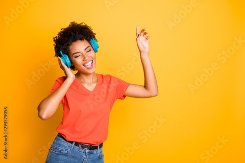 Photo of cute charming curly wavy trendy attractive black american girlfriend wearing t-shirt jeans denim dancing singing with her eyes closed isolated over yellow vivid color background