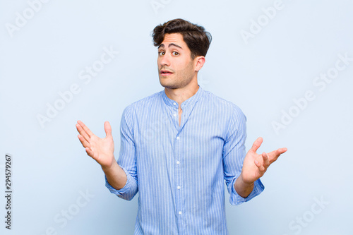 young handsome man looking nervous, anxious and concerned, saying not my fault or I didn‚Äôt do it against blue background photo