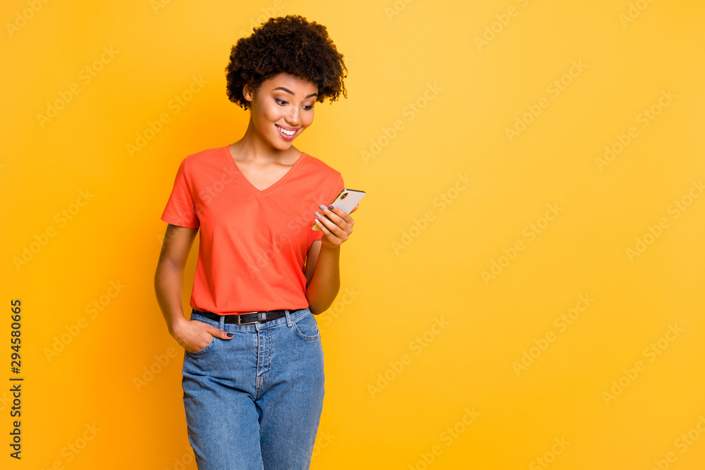 Copyspace photo of beautiful cheerful cute charming gorgeous girlfriend standing confidently wearing t-shirt jeans denim holding phone isolated over yellow color vivid background Copyspace photo of beautiful cheerful cute charming gorgeous girlfriend standing confidently wearing t-shirt jeans denim holding phone isolated over yellow color vivid background