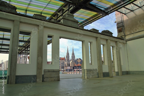 Structure and roof of a train station interior on background of spires towers of Sint-Petrus-en-Pauluskerk the main church of Ostende  Belgium. train station  europe