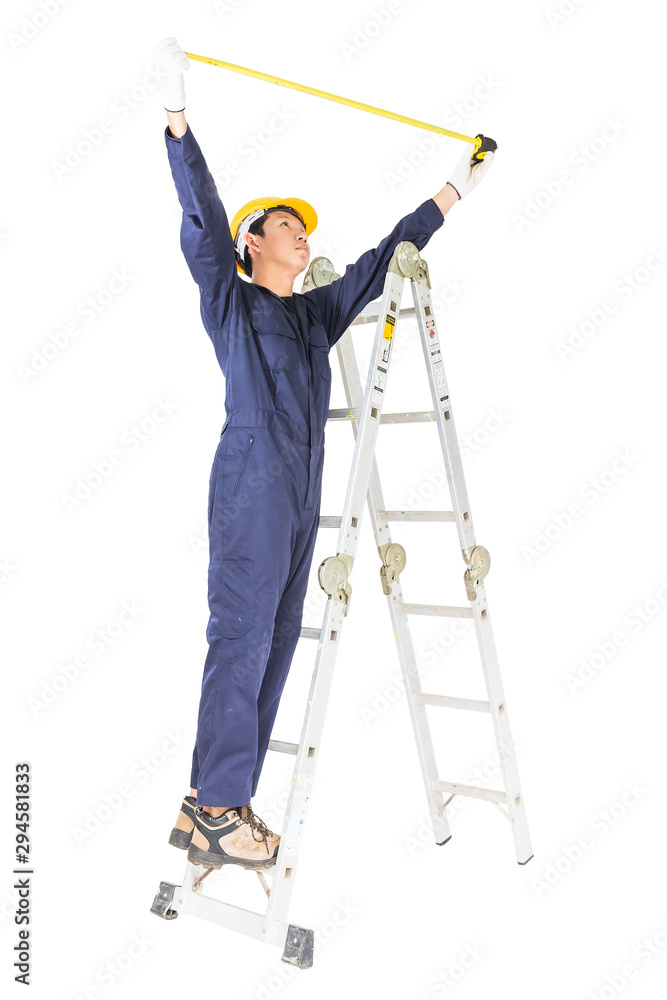 Handyman in uniform standing on ladder while using tape measure on white Handyman in uniform standing on ladder while using tape measure on white