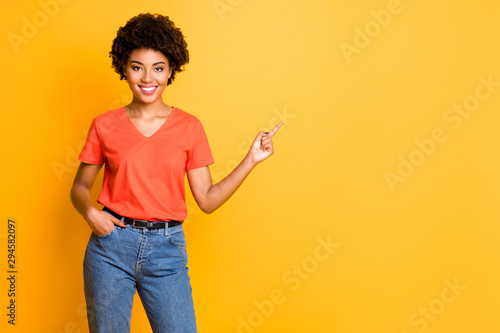 Copyspace photo of attractive fascinating cute pretty confident girlfriend black american pointing at space to be fulfilled wearing denim t-shirt while isolated yellow vibrant color background