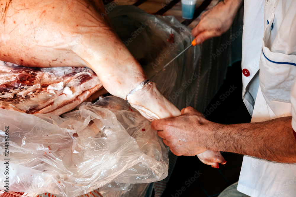 close up of a butcher cutting a pig carcass