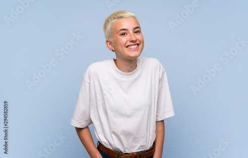 Teenager girl with white short hair over blue wall laughing