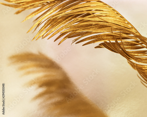 Close-up natural palm leaf painted golden metallic colored. Trend color plant...
