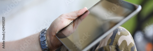 Focus on male hands holding stylish gadget and surfing internet. Man sitting outdoors and messaging via special app. Copy space on empty screen. Blurred background
