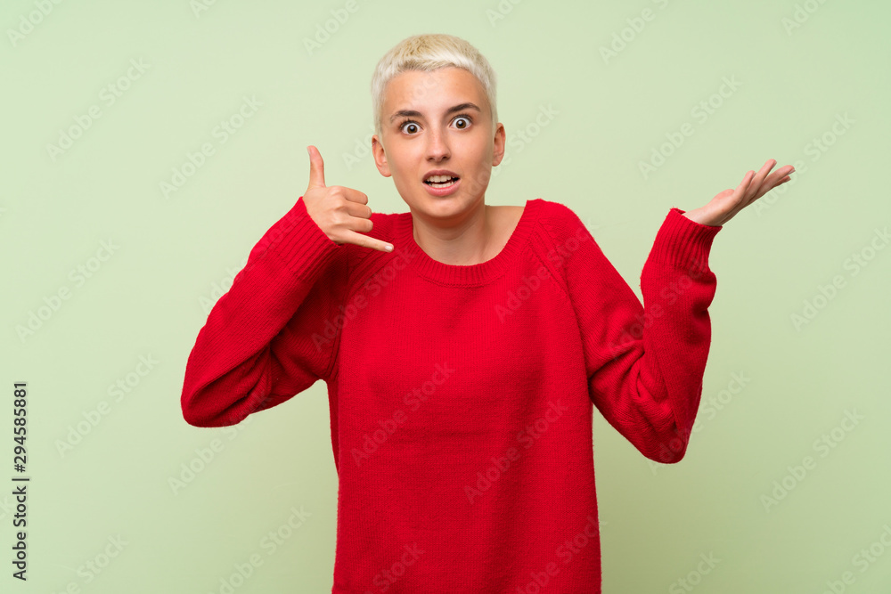 Teenager girl with white short hair over green wall making phone gesture and doubting Teenager girl with white short hair over green wall making phone gesture and doubting