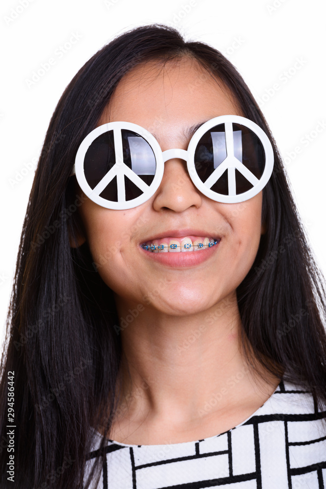 Face of young happy Asian teenage girl smiling while wearing sun Face of young happy Asian teenage girl smiling while wearing sun