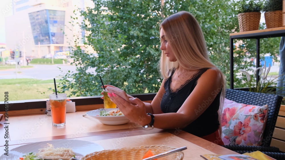 beautiful blonde woman chatting on the phone, female waiting for a meeting, sitting in a cafe on the street. beautiful blonde woman chatting on the phone, female waiting for a meeting, sitting in a cafe on the street.