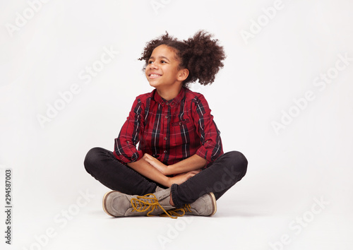Cute teenage girl in casual stylish clothes sitting against white background