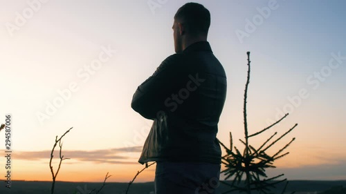 Man stands on top and looks at the sunset with different clouds in the sky. Close up slow motion epic footage. 4k.