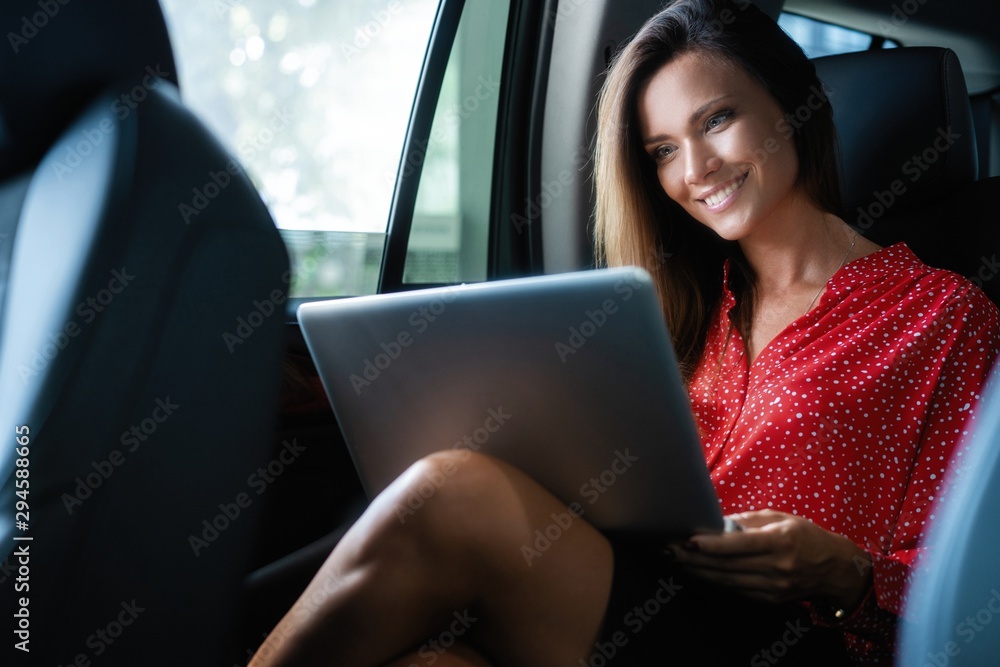 Businesswoman inside her car using a laptop.