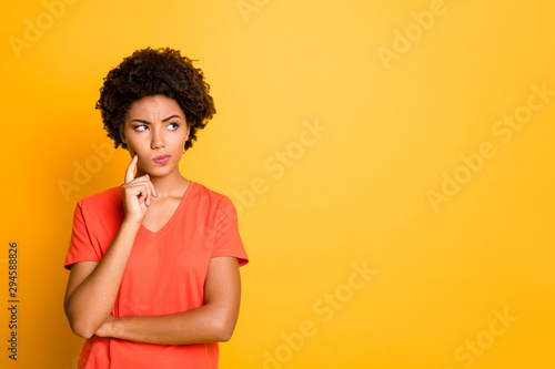 Photo of funny dark skin lady doubtful about making important decision wear orange v neck t-shirt isolated yellow color background