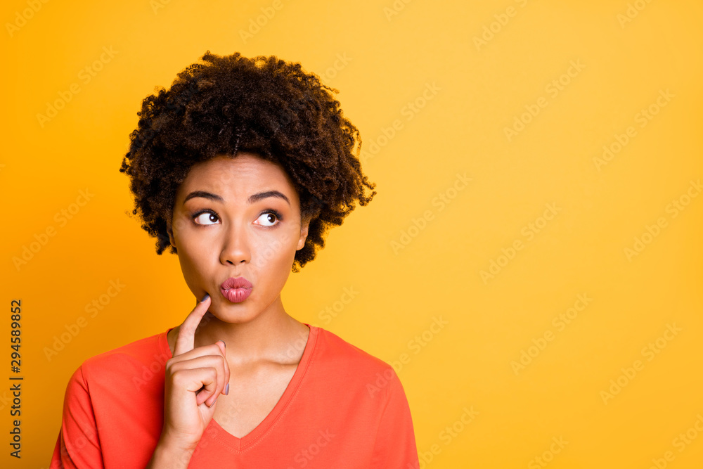 Photo of amazing dark skin lady think over important business stuff look empty space wear orange v neck t-shirt isolated yellow color background Photo of amazing dark skin lady think over important business stuff look empty space wear orange v neck t-shirt isolated yellow color background